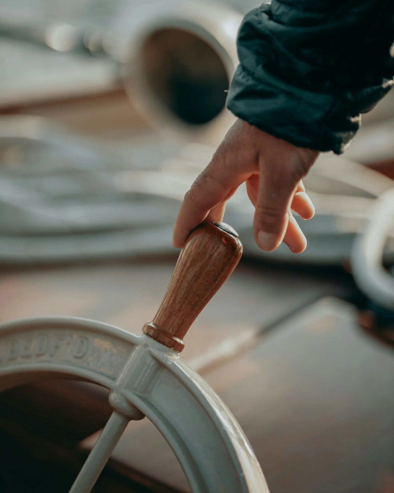 Une main posée sur la barre à roue d’un bateau.